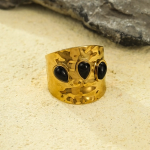 Macro detail of French vintage gold hammered wide ring with three black gemstones