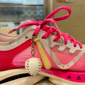 Close-up of pink sneaker featuring a miniature baseball and bat keychain accessory