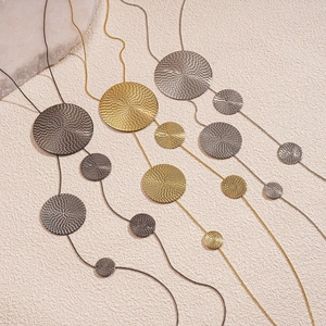 Three long necklaces in black, gold, and silver finishes with hammered round pendants