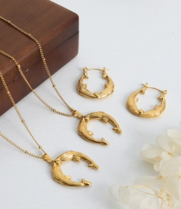 Detailed set of whale-shaped gold pendants and hoop earrings on elegant wood display