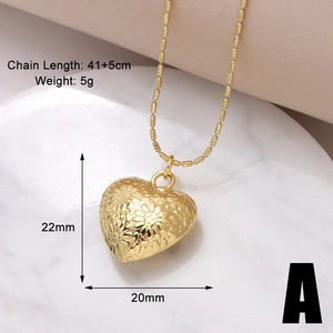 Detail of gold heart pendant with floral engraving on pink silk showing size and weight