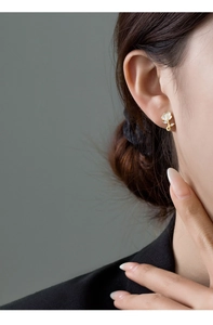 Detail view of a white rose earring with zircon inlay worn by a model on ear