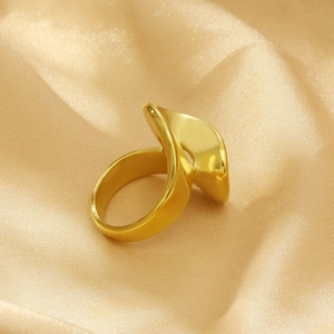 Macro shot of gold irregular geometric ring on smooth champagne satin fabric texture