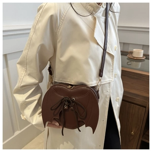 Detail of bat wing heart bag showing cross-lace design on brown matte leather