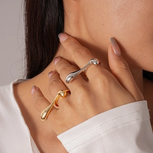 Close-up of gold and silver irregular lava rings worn by a model in a warm setting