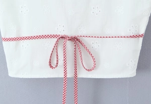 Close-up of white embroidered floral top with red and white checkered tie detail