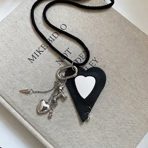 Minimalist leather heart and dog pendant necklace on a braided black cord over a book