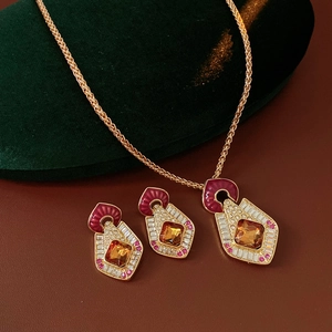 Detail of vintage golden jewelry set with amber stones and red enamel on velvet