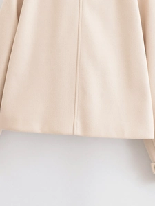 Close-up of beige wool fabric texture and high-quality stitching on a cropped jacket