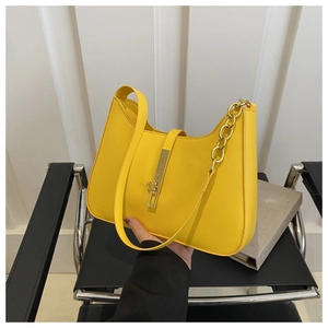 Detail of yellow pebbled leather shoulder bag with golden horseshoe clasp and chain