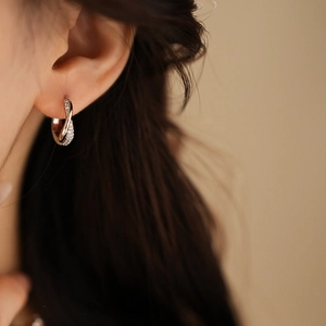Close-up of twisted silver hoop earrings with cubic zirconia worn by a female model