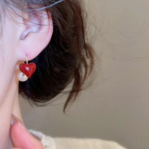 Dettaglio degli orecchini con cuore rosso e perla su modella in stile vintage