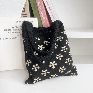 Dettaglio della borsa tote in maglia nera con motivi a margherita e trama morbida
