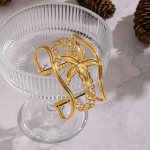 Exaggerated wide hollow starfish cuff bracelet with 18K gold plating on marble surface