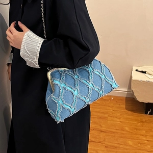 Quilted blue denim shell bag with gold clasp and chain strap shown on a model