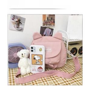 Close-up of pink canvas crossbody bag with animal ears and a functional front pocket