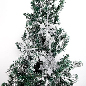 Clear acrylic Christmas snowflake ornaments with silver glitter hanging on a frosted tree
