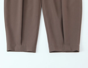 Gros plan d'un pantalon marron montrant des coutures précises et la texture du tissu