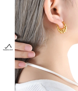 Close-up of golden twist texture on stainless steel U-shaped hoop earrings for women