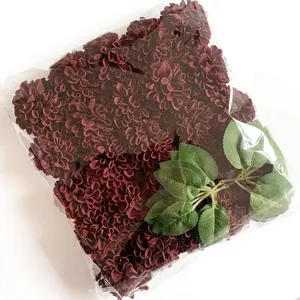 Dark red artificial hydrangea and rose bouquet with green leaves in clear packaging