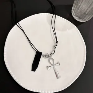 Dettaglio del ciondolo croce Ankh in argento martellato con cordini neri