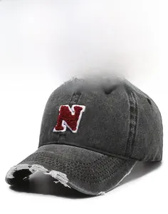Detail of distressed brim and red N-letter chenille embroidery on denim baseball cap