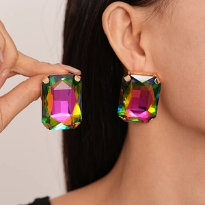 Close-up of oversized gold-toned earrings featuring aurora crystal stones in a four-prong setting