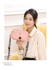 Detailed shot of pink woven crossbody bag with cat charm and wide jacquard strap