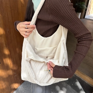 Detail view of the interior zip pocket and lining inside the cream pleated tote bag
