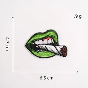 Dettaglio patch ricamata con labbra verdi e sigaretta, misura 6.5 x 4.3 cm