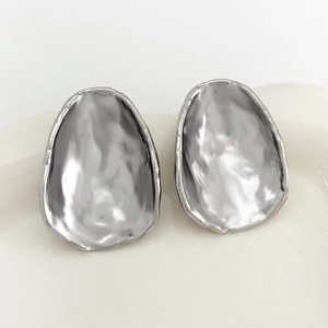 Detail of silver irregular oval metal earrings with polished glossy surface texture