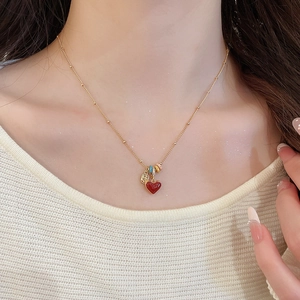 Close-up of model wearing 18k gold plated heart necklace with red pendant and colorful beads