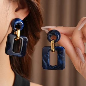 Detailed close-up of dark blue marble resin geometric drop earrings with gold metal links