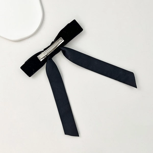 Detailed view of black velvet bow hair clip with long ribbons and metal duckbill clip