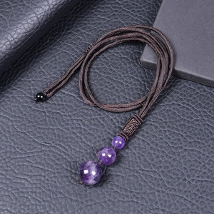 Macro shot of three natural amethyst stone beads on a dark brown braided rope necklace