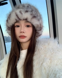 Close-up of leopard print faux fur bucket hat and white plush winter coat on model