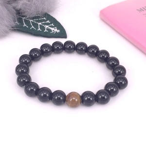 Detalle de pulsera de hematita con cuenta de ojo de tigre sobre fondo de terciopelo suave