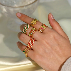 Close-up of stacked 18K gold plated stainless steel rings with colorful enamel on silk fabric