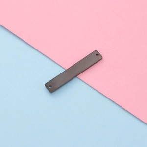 Close-up of a black rectangular stainless steel two-hole connector tag on colorful background
