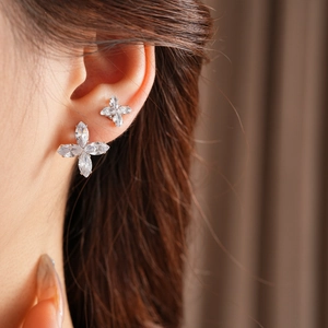 Gros plan de boucles d'oreilles fleur à quatre feuilles en zircon sur l'oreille du mannequin