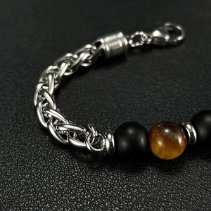 Close-up of men's steel chain bracelet with tiger eye stone and black beads on leather