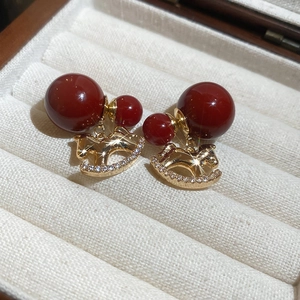 Macro shot of 18K gold plated rocking horse earrings with red beads and zircons
