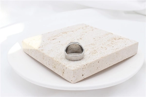 Close-up of a minimalist silver wide band ring placed on a textured stone prop