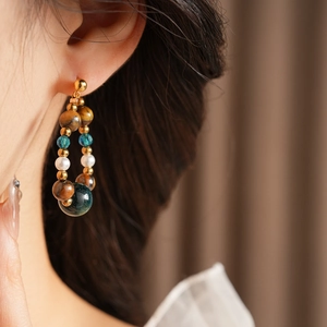 Gros plan d'un mannequin portant des boucles d'oreilles en œil de tigre et perles