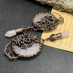 Detailed shot of bronze dragon carving on rose quartz crystal pendant with vintage aesthetic