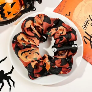 Detail of Halloween pumpkin pattern scrunchie in smooth satin on a festive white plate