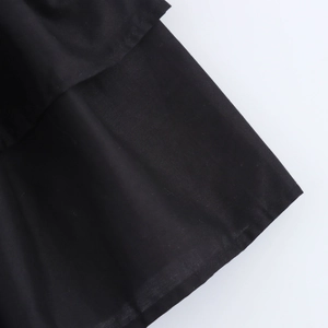 Détail du tissu noir multicouche et des coutures de précision sur l'ourlet de la robe