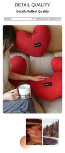 Detail of red heart-shaped cushion with Happy Home label in cozy living room setting