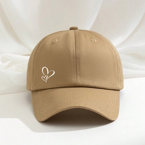 Khaki cotton baseball cap with white heart print shown on a textured fabric background