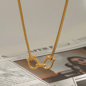 Gold stainless steel snake chain necklace with double ring buckle on vintage newspaper